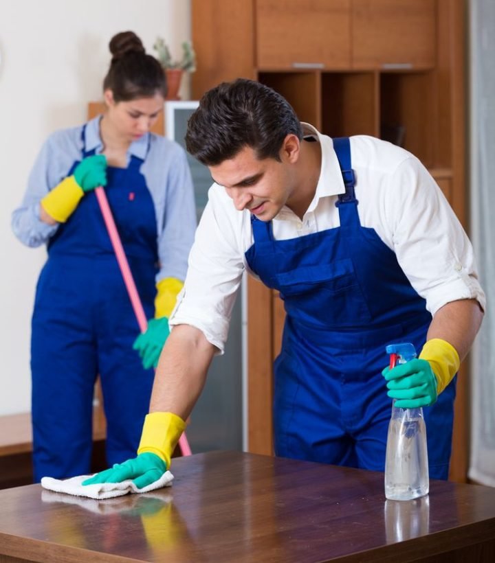 Young man and woman in overalls cleaning and dusting